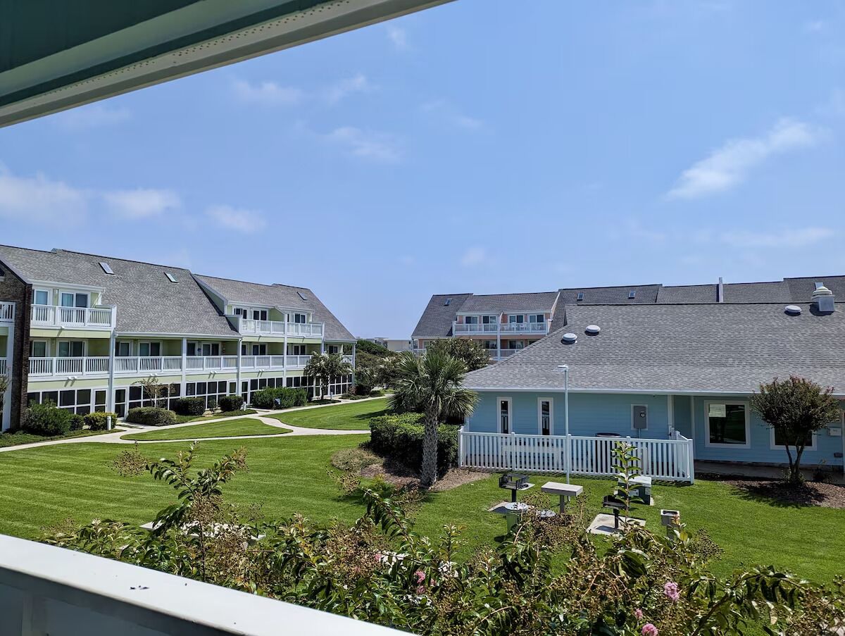 Ein Wohnhauskomplex mit mehreren zweistöckigen Häusern, einem gepflegten Rasen und blauem Himmel.