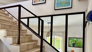 A staircase with beige steps and black railings, leading to a room with a large window and artwork on the walls. - Villa Azul - Welkeys (Bandol)