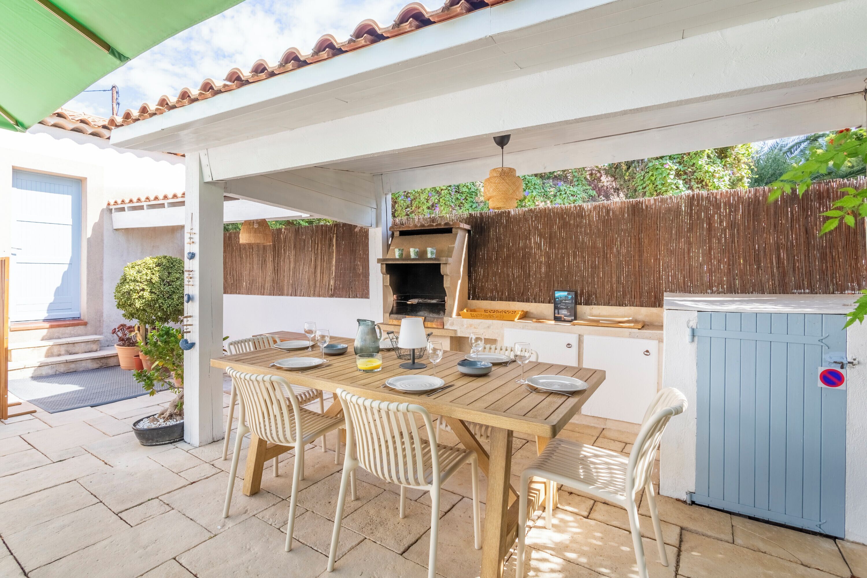 Eine Terrasse im Freien mit einem Holztisch, der zum Essen gedeckt ist, einem Grill und einem blauen Stauraumschrank.