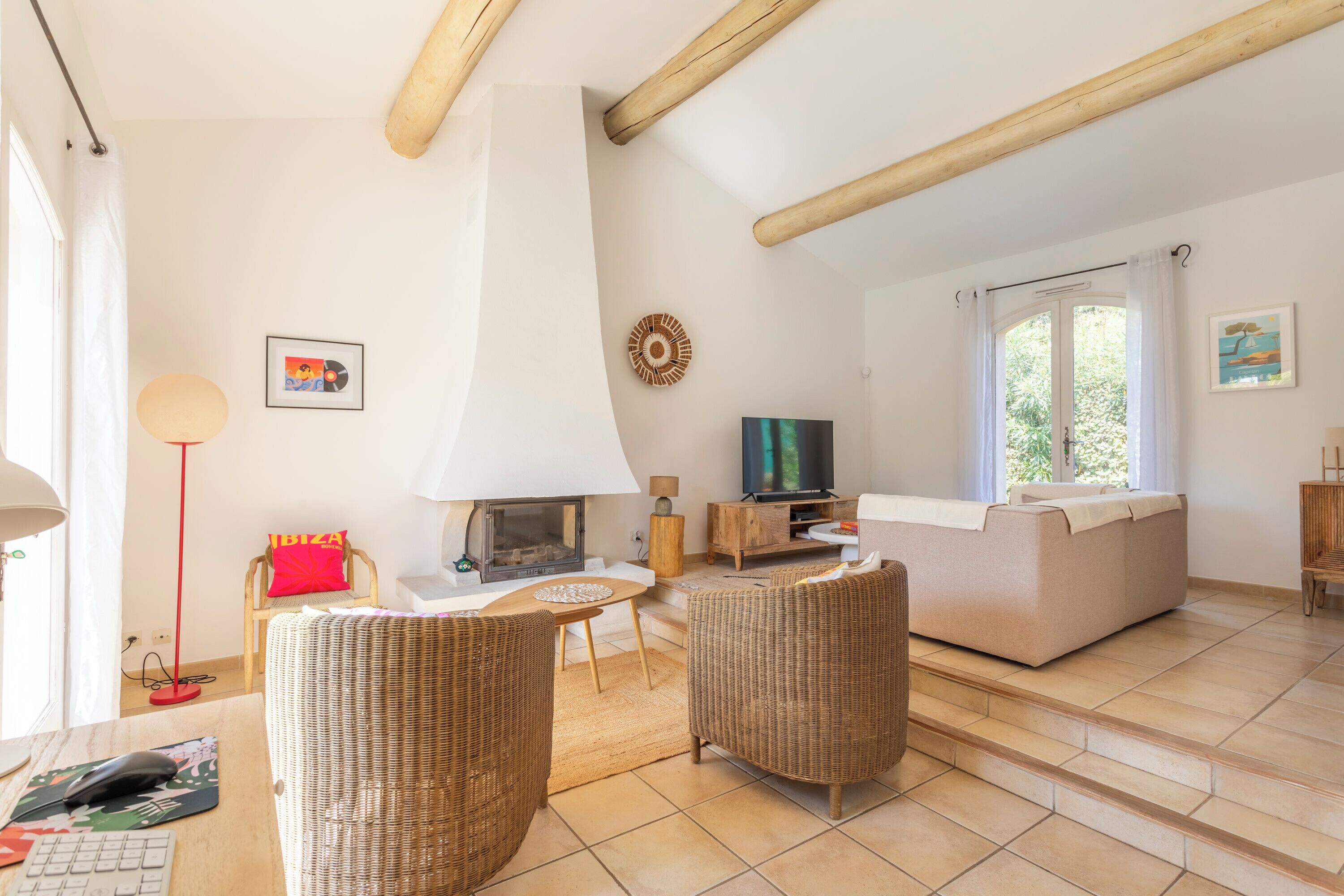 A living room with a fireplace, wicker furniture, a sofa, and a television.