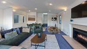Un salon moderne comprenant un canapé, des fauteuils, une table basse, une cheminée et un téléviseur.