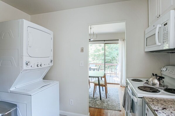 A compact kitchen with a washer-dryer unit, a microwave, and a stove.