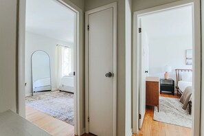A bedroom with a bed, bedside table, lamp, and a view of a cityscape through a window.