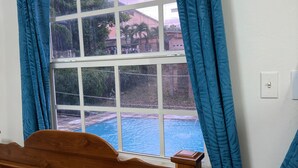 A room with a wooden bed, orange bedding, and a window with blue curtains.