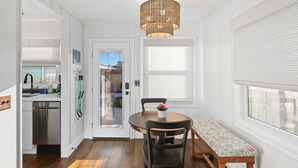 A compact kitchen with a dishwasher, a dining table with chairs, a bench, and a wicker chandelier. - 1 Block to Ocean * Brand New Remodel * Dog OK! (San Diego)