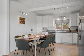 A modern kitchen with white cabinetry, a stainless steel refrigerator, and a dining area with a table set for six. - Sunnyside Resort Spa, Beach, Zoo, Arcade (La Mesa)