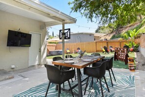 An outdoor patio area with a table set for dining, surrounded by chairs, and a covered seating area with chairs and a table. - Sunnyside Resort Spa, Beach, Zoo, Arcade (La Mesa)