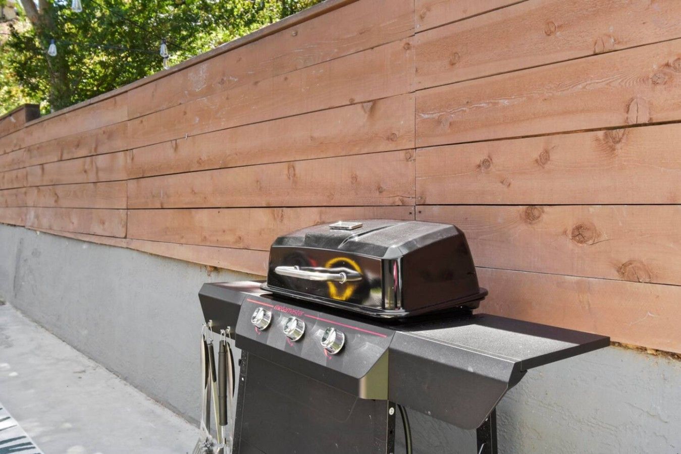 A portable grill with a digital display and control knobs, positioned against a wooden wall.