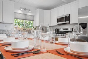 Una cocina moderna con gabinetes blancos, electrodomésticos de acero inoxidable y un comedor listo para una comida.