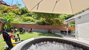 Un patio trasero con jacuzzi, mobiliario exterior y una valla de madera.