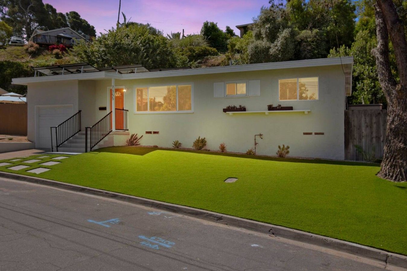 A modern two-story house with a well-maintained lawn, a front door, and a staircase leading to the entrance.