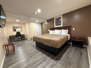 Una habitación de hotel con cama, escritorio, silla y televisor.