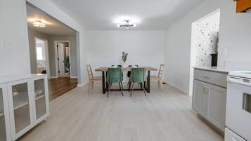 A modern kitchen with white cabinetry, a dining table with chairs, and a visible oven.