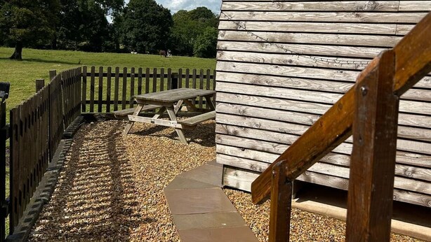 A wooden structure with a picnic table and a wooden fence. - Rural Cosy Cabin with Wood-Fired Hot Tub (Whitchurch)