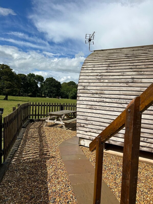 A wooden structure with a picnic table and a wooden fence. - Rural Cosy Cabin with Wood-Fired Hot Tub (Whitchurch)