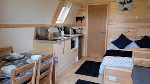 A compact, wooden cabin with a kitchen, dining area, and sleeping quarters. - Rural Cosy Cabin with Wood-Fired Hot Tub (Whitchurch)