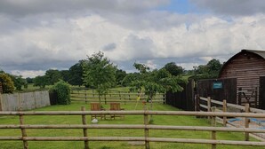 A fenced outdoor area with a wooden structure, possibly a barn, and a grassy field. - Rural Cosy Cabin with Wood-Fired Hot Tub (Whitchurch)