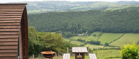 Un bâtiment en bois avec une table et un banc donnant sur une vallée verdoyante.