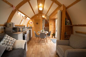 Eine gemütliche, gut beleuchtete Zelthütte mit Essbereich, Küche und Sitzgelegenheit.
