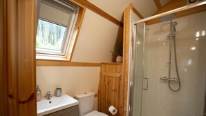 Un baño con ducha, inodoro, lavabo y ventana.
