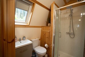 Un baño con ducha, inodoro, lavabo y ventana.