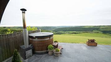Una terrazza con vasca idromassaggio, posti a sedere e piante in vaso.