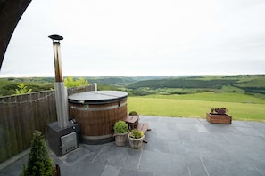 A patio with a hot tub, seating, and potted plants.