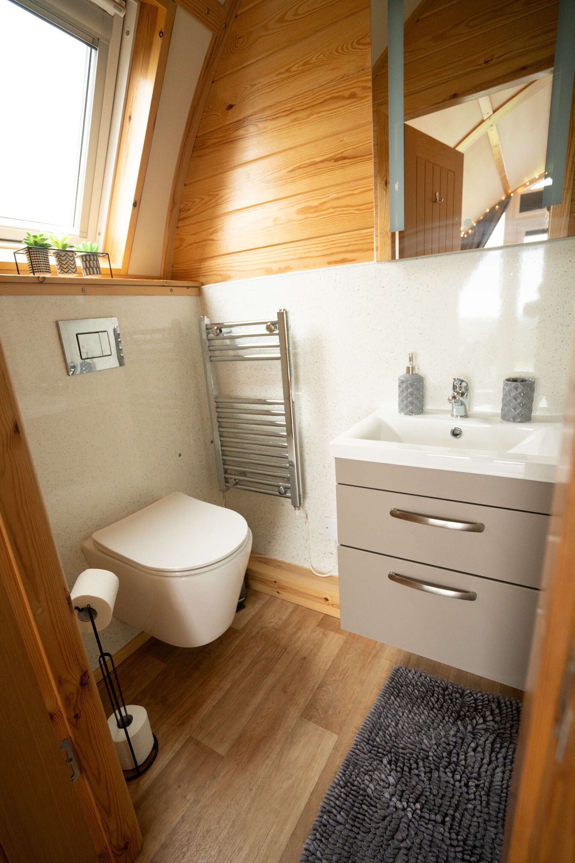 A compact bathroom with a toilet, sink, and towel rack.