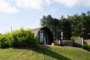 Un bâtiment moderne doté d’un toit incurvé, entouré d’une végétation luxuriante et de grands arbres.