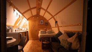 Un intérieur chaleureux avec un plafond en bois, un lit avec des oreillers, une petite table et une chaise.