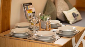 Una mesa de comedor ordenada con platos, vasos y una pequeña planta en maceta.