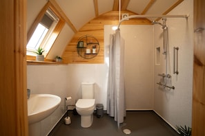 Een kleine, compacte badkamer met dakraam, toilet, wastafel en douche.