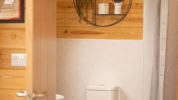 Een kleine badkamer met een wit toilet, een klein afvalbakje en een douchegordijn.