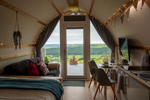 Un dormitorio acogedor con cama, escritorio y vistas al campo.