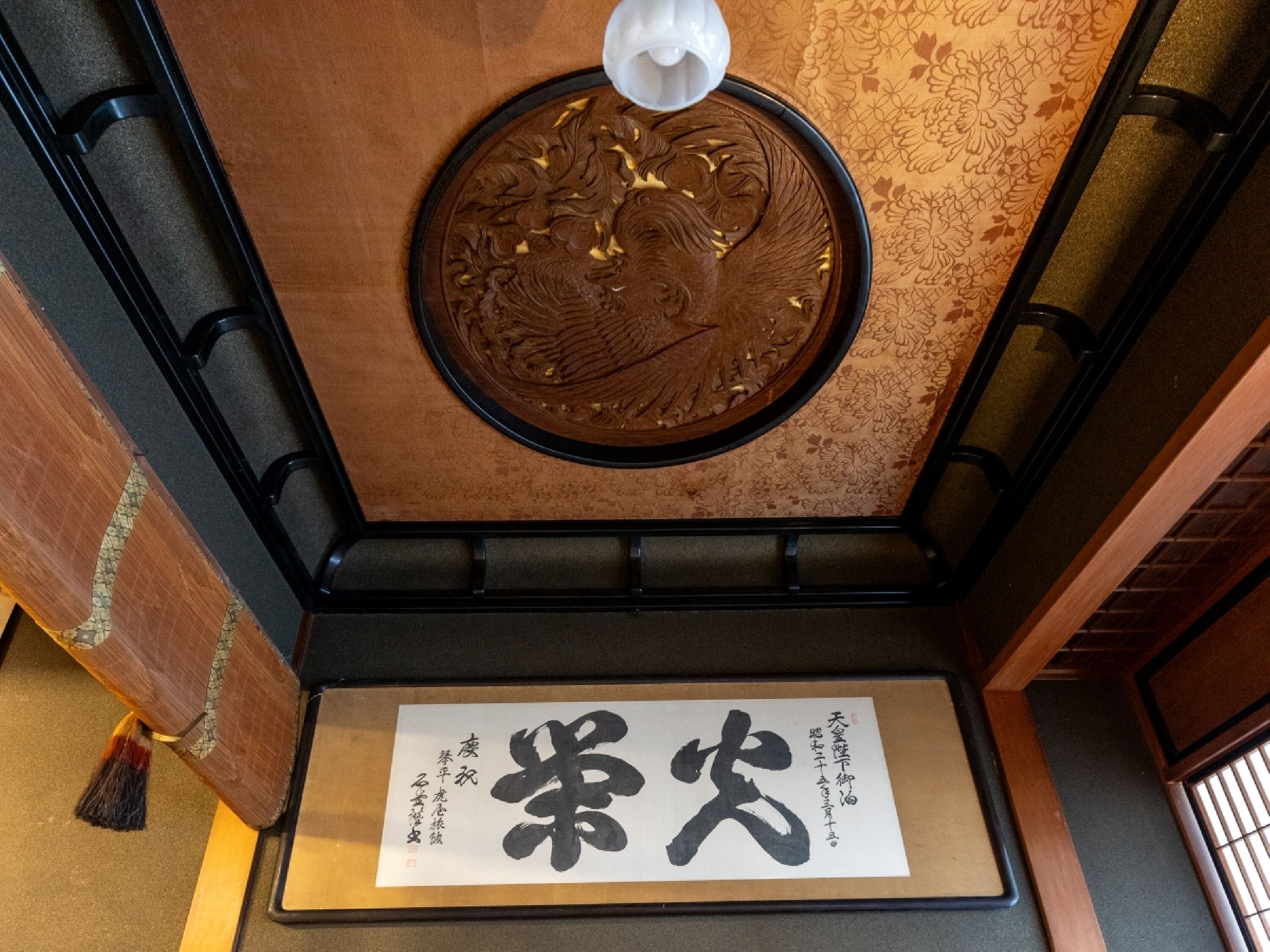 A traditional Japanese room with tatami flooring, a shoji screen, and a decorative wooden ceiling.