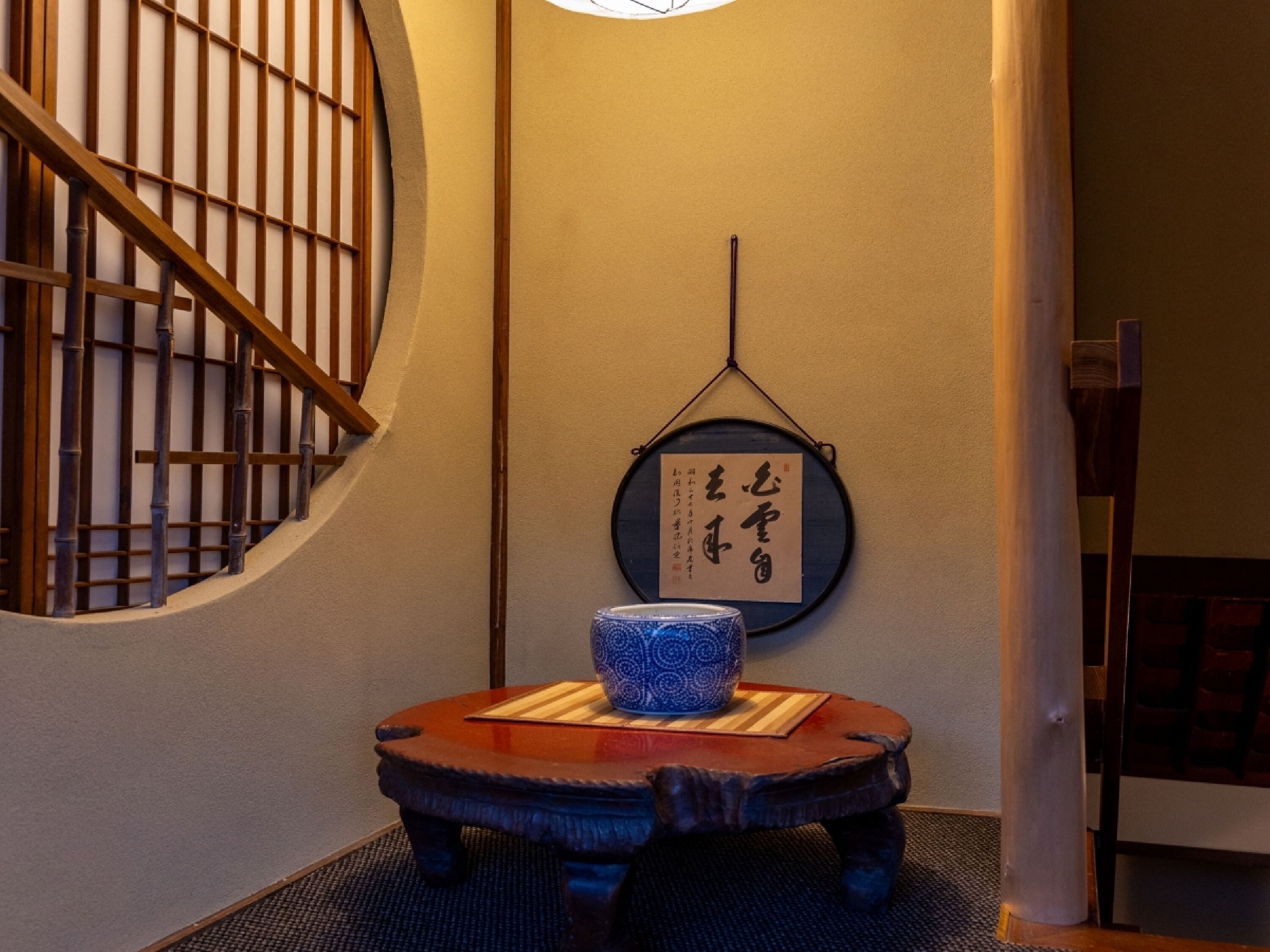 A traditional Japanese room with tatami flooring, a low wooden table with a blue ceramic bowl, and a shoji screen with a hanging scroll.