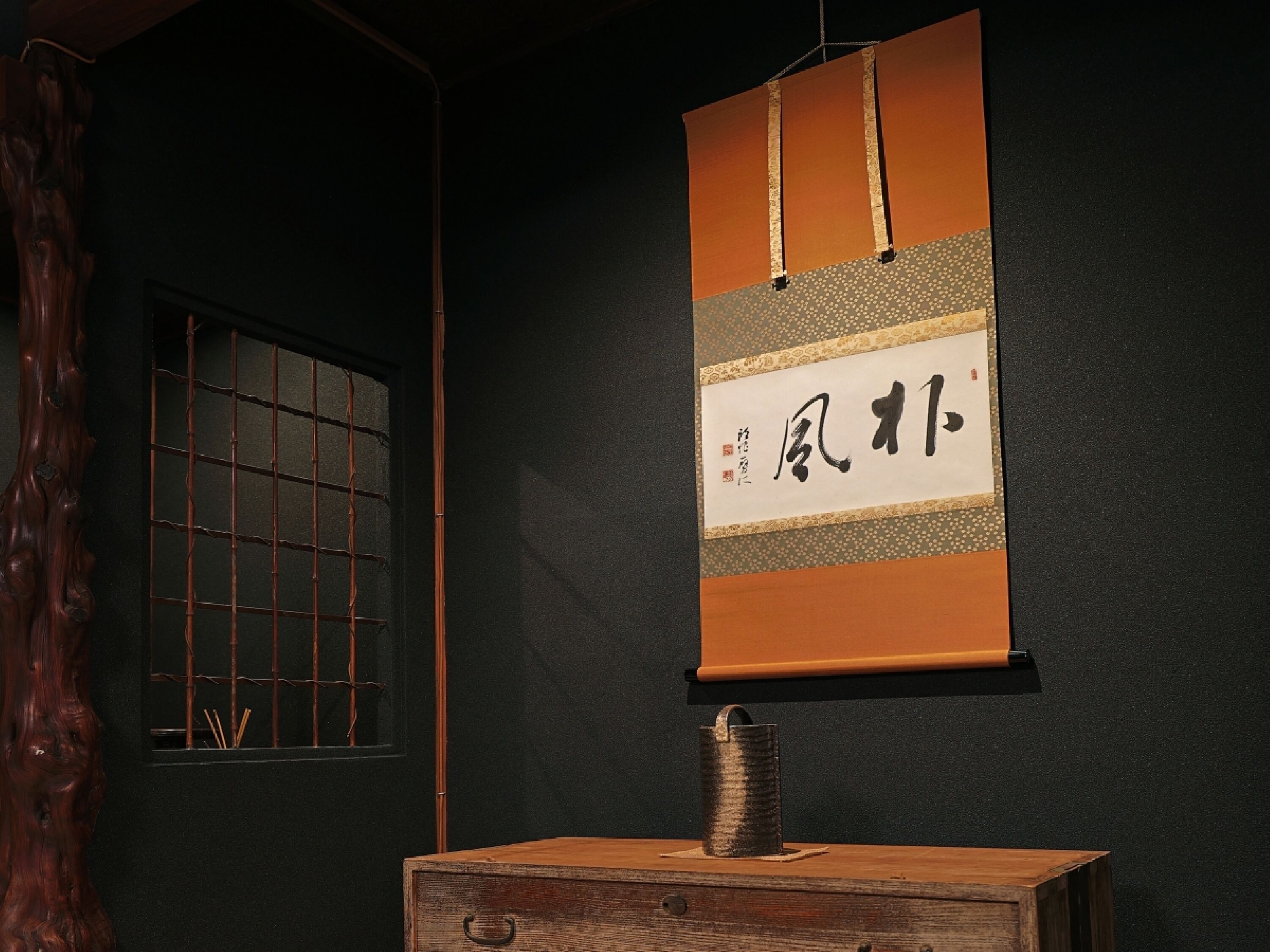 Una habitación japonesa tradicional con suelo de tatami, puerta corrediza shoji y un pergamino colgado con caligrafía.