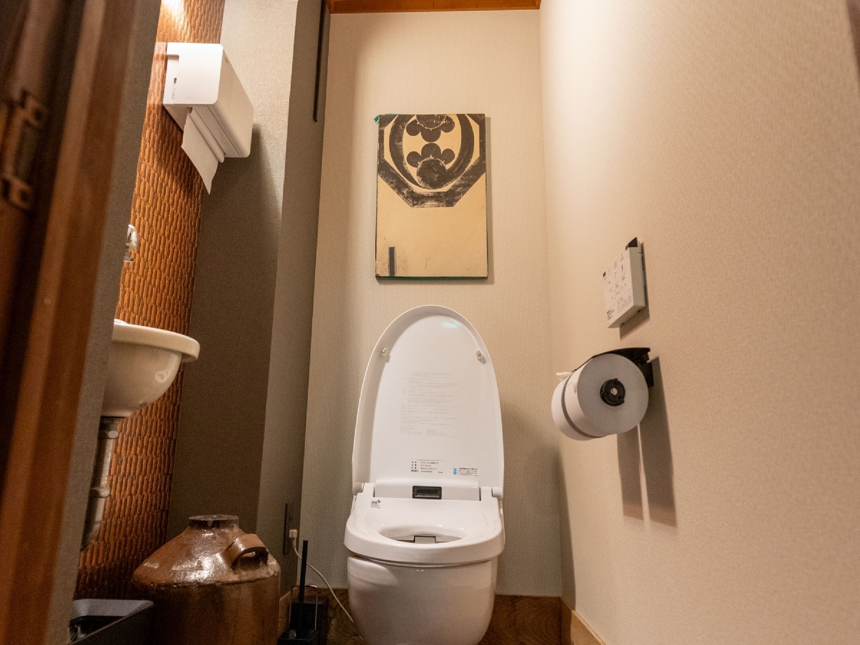 Un baño pequeño con inodoro, dispensador de toallas de papel y un adorno en la pared.