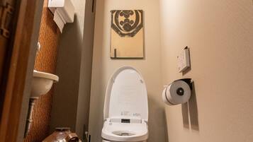 Un baño pequeño con inodoro, dispensador de toallas de papel y un adorno en la pared.