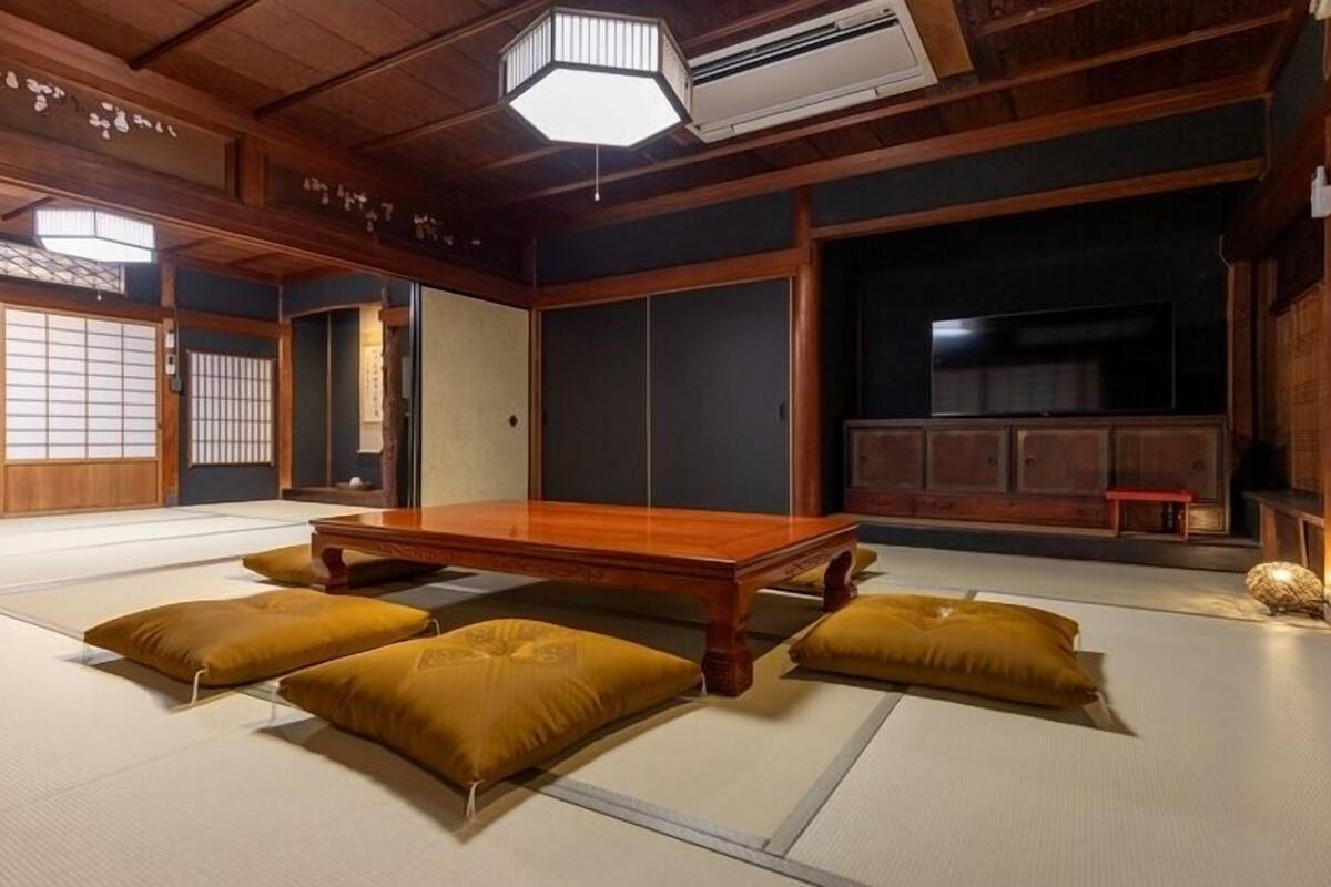 A traditional Japanese room with tatami flooring, a low wooden table, and cushions.