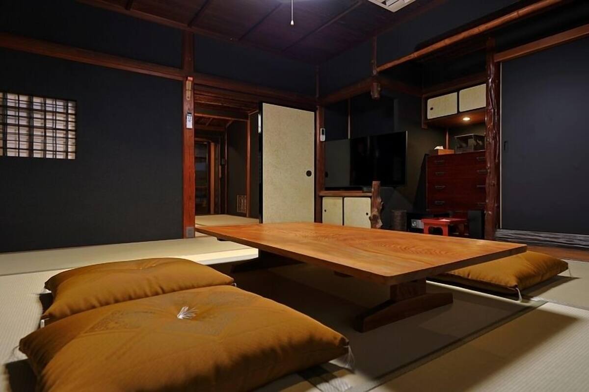 A tatami mat room with a low wooden table, cushions, and sliding doors.