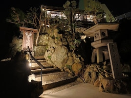Un templo japonés tradicional con escalones de piedra que conducen a una estructura de madera, rodeado de rocas y árboles.