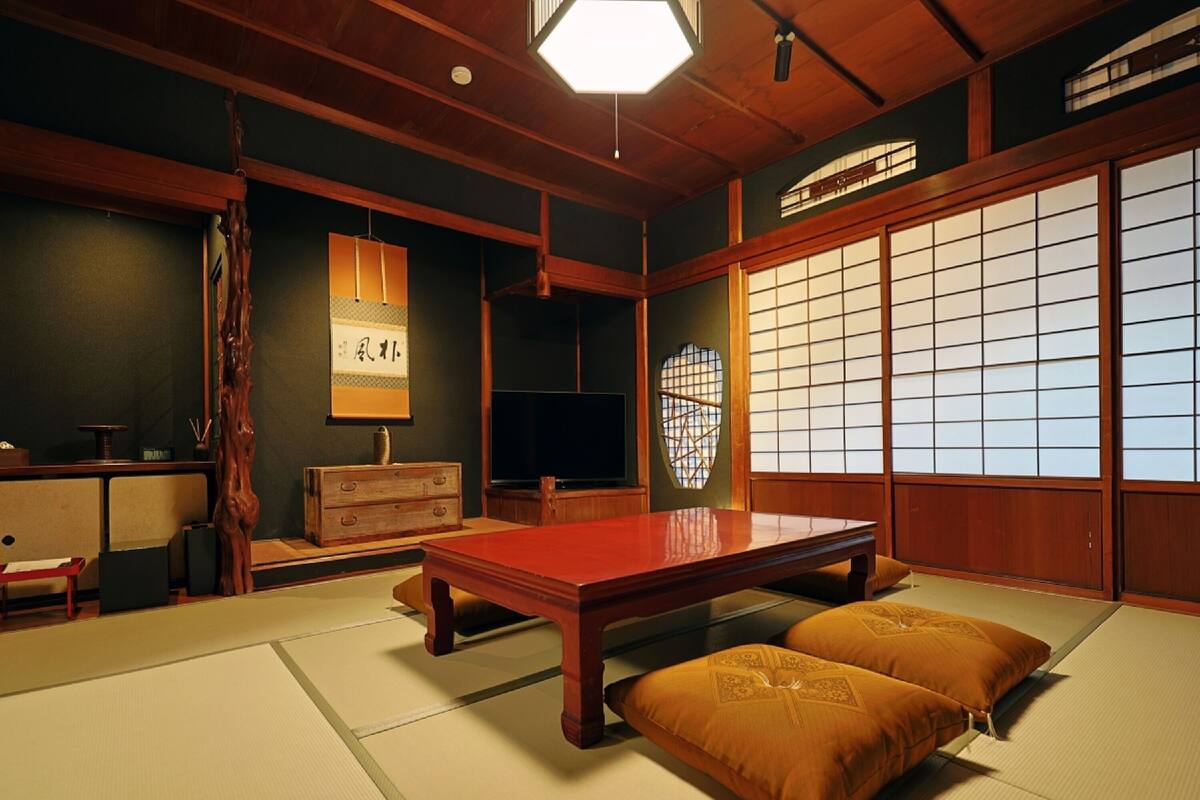 A traditional Japanese tatami room with a low wooden table, cushions, and sliding doors.