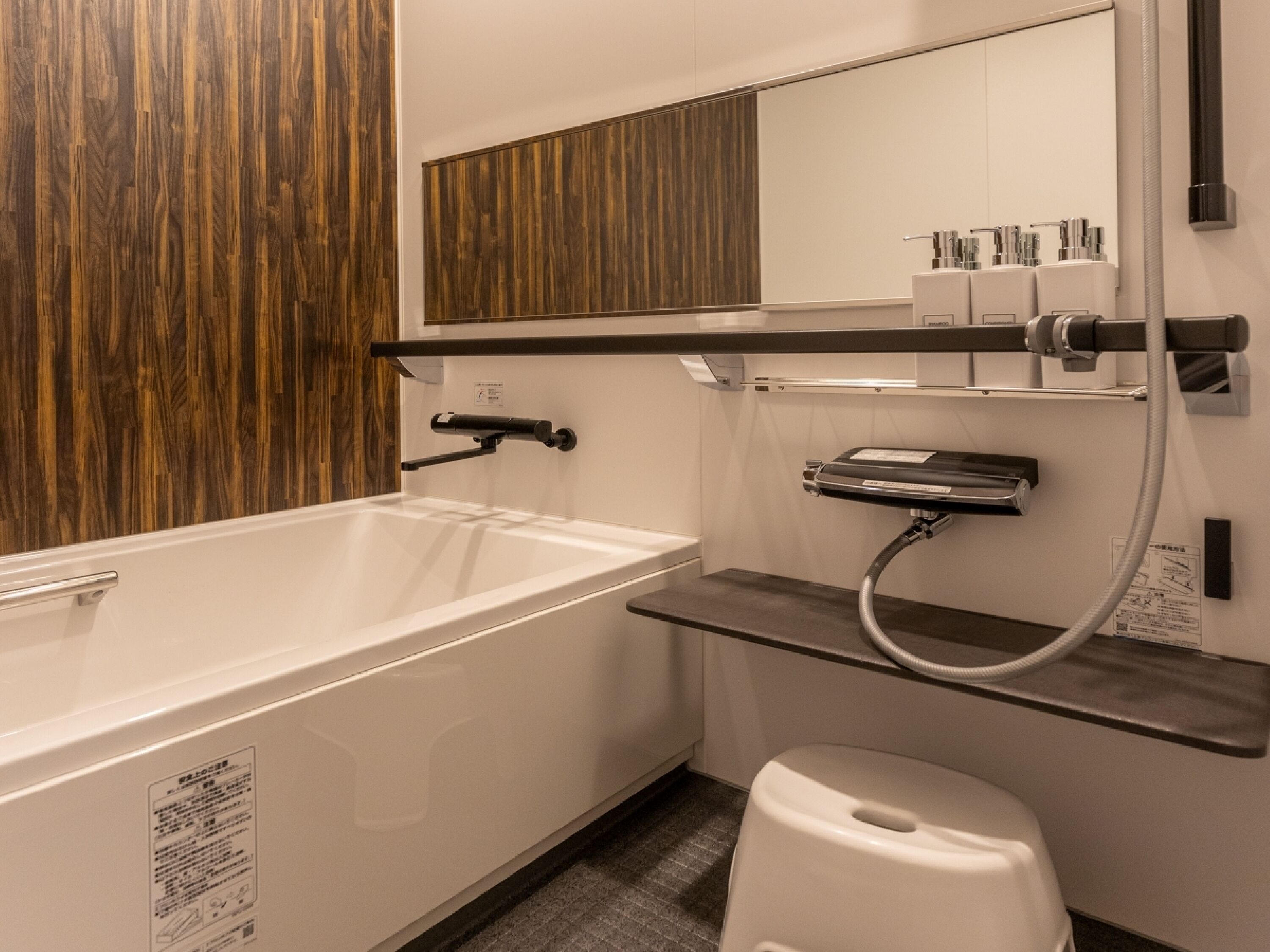 A modern bathroom with a white bathtub, a wooden panel wall, a mirror, and a shelf with toiletries.