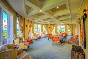A spacious lounge with multiple seating areas, large windows, and a ceiling with a geometric pattern. - Inlet #608 - 3BD 2BA Ravishing Panoramic Vista (New Smyrna Beach)