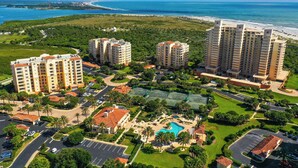 A high-rise hotel with multiple floors, a central courtyard with a swimming pool, and a beach view. - Ravishing Panoramic Vista | Inlet #608 (New Smyrna Beach)