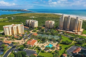 A high-rise hotel with multiple floors, a central courtyard with a swimming pool, and a beach view.