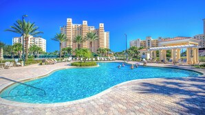 A swimming pool with a hexagonal tiled deck, surrounded by palm trees and lounge chairs. - Ravishing Panoramic Vista | Inlet #608 (New Smyrna Beach)