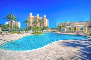 A swimming pool with a hexagonal tiled deck, surrounded by palm trees and lounge chairs.
