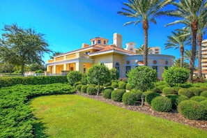 A large, multi-story building with a curved roof, surrounded by well-manicured gardens and palm trees. - Inlet #608 - 3BD 2BA Ravishing Panoramic Vista (New Smyrna Beach)